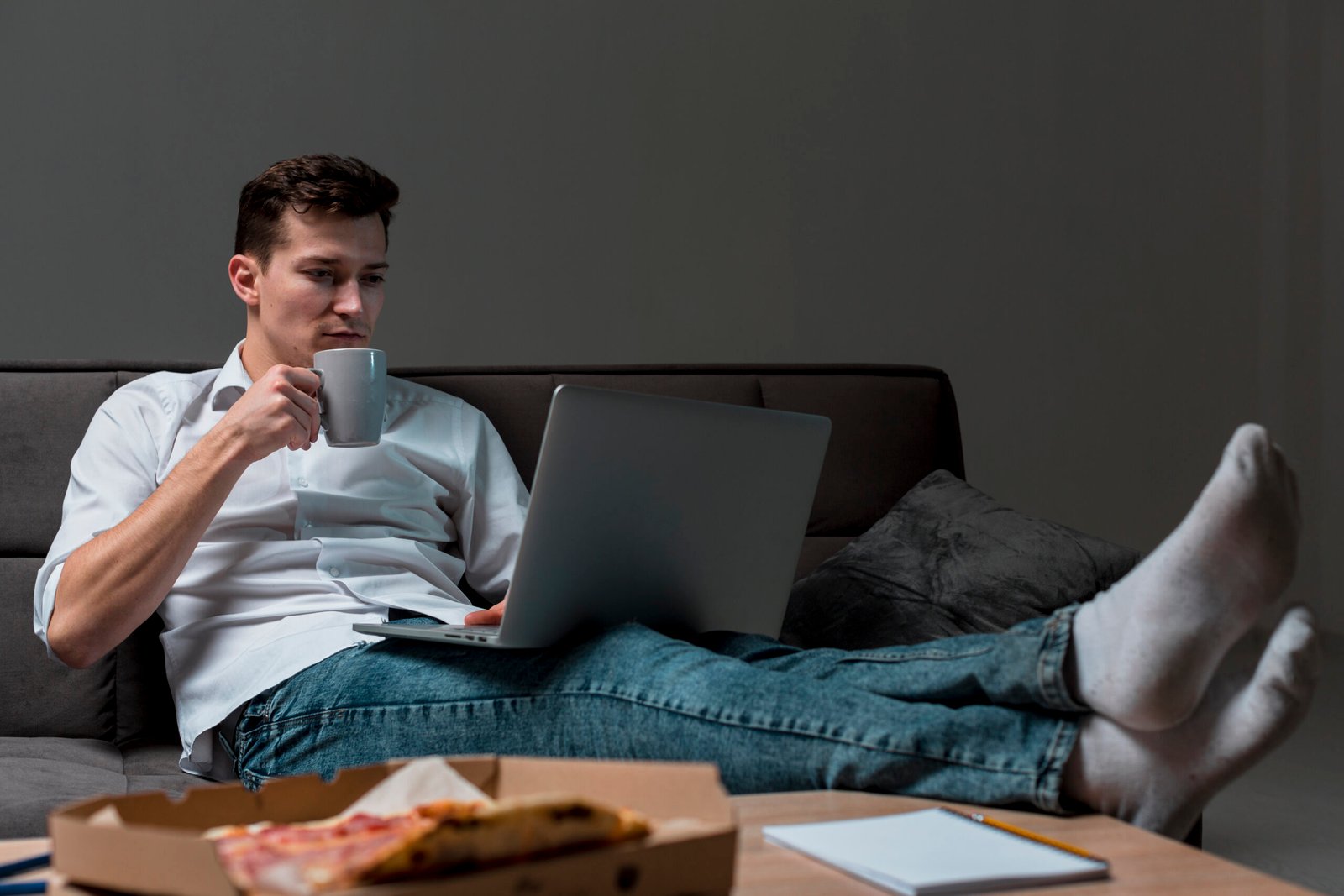 A student casually working on a laptop while drinking coffee illustrating the flexibility of remote learning with AI tools for students and online study platforms